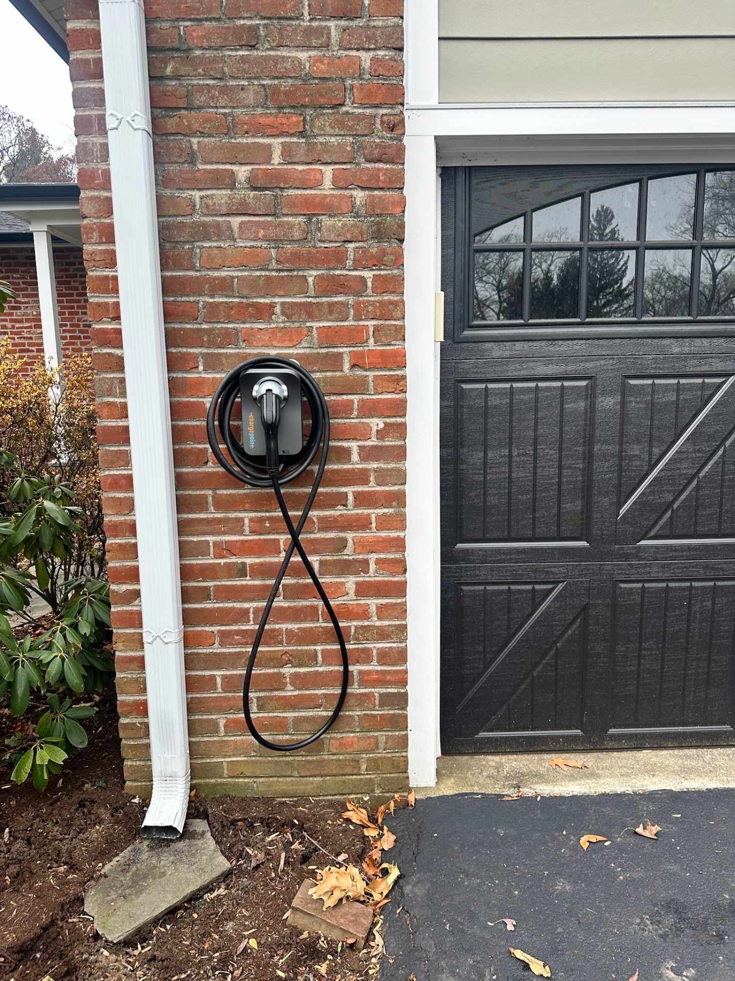 ChargePoint Home Flex EV charger installed on a brick exterior wall next to a residential garage door
